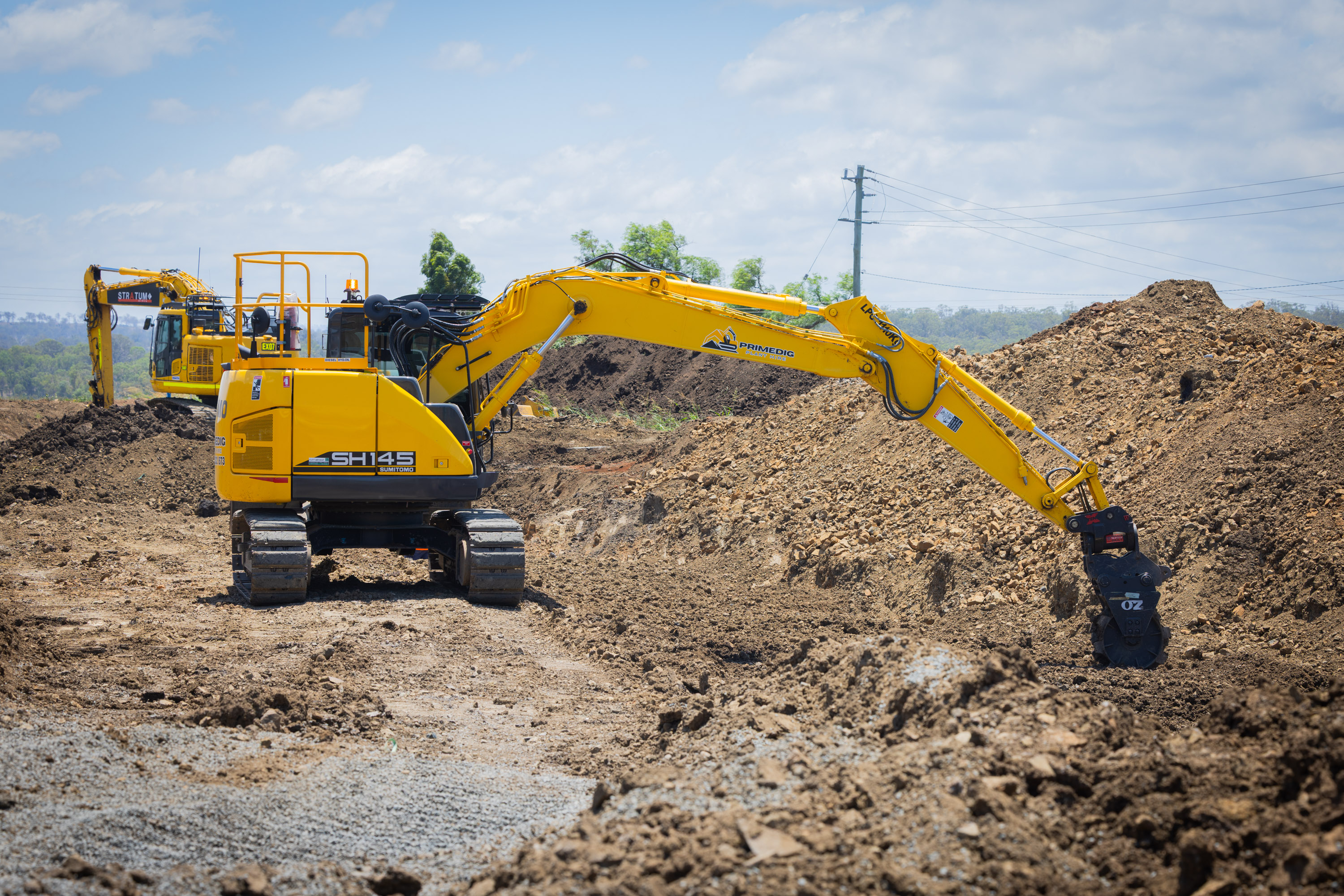 Sumitomo excavator shaping spoil mounds on a bulk earthworks site